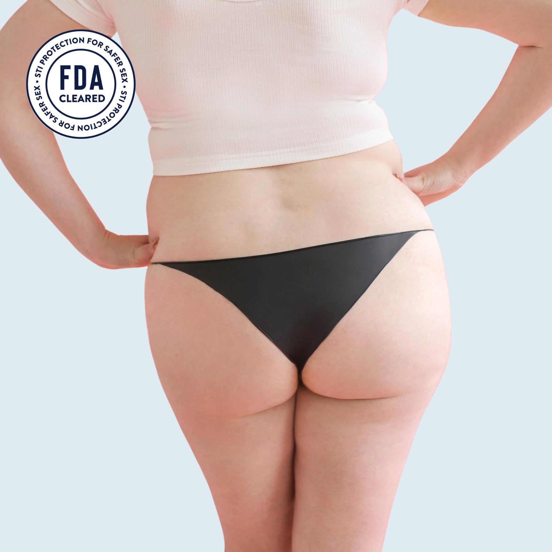 Lorals model Amanda demonstrates the back view of Black Latex STI Protection Panties in Bikini Style